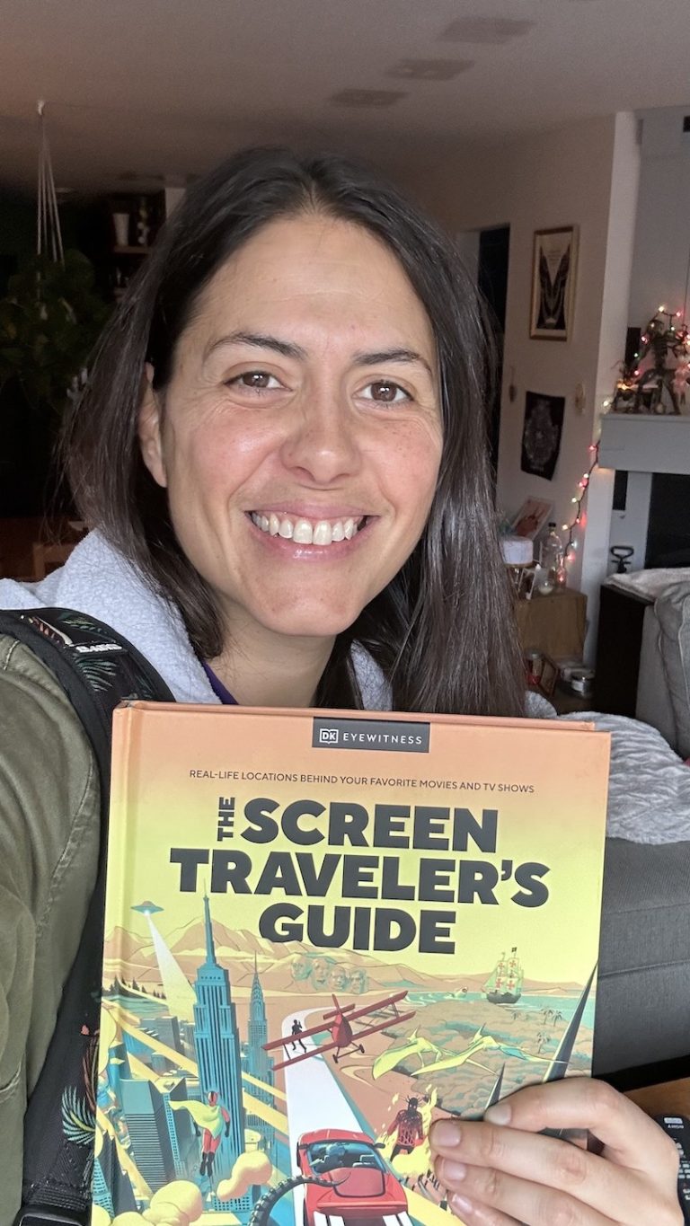 Gem Seddon grinning like a dork holding a copy of The Screen Travelers Guide book